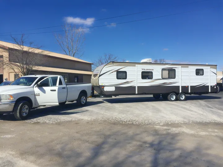 White pickup truck hitched to a Wildwood travel trailer, an RV rental ready for the road.. Forest River Wildwood 2018