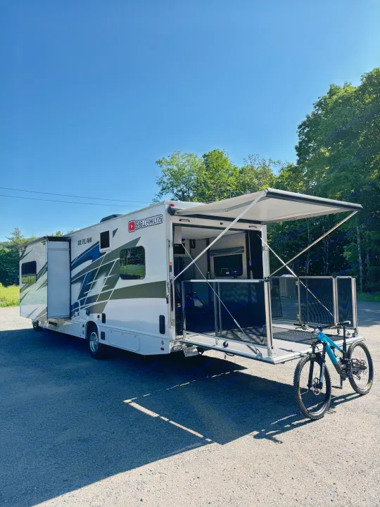 Discover the ultimate RV rental! This white toy hauler RV features an open patio deck and a mountain bike, perfect for adventures.. Thor Outlaw 2024