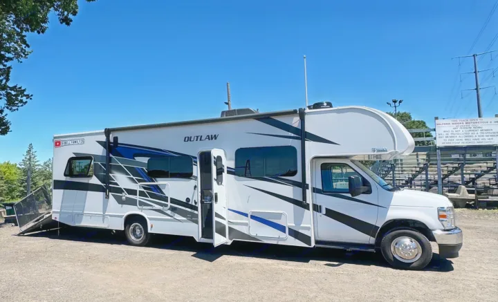 White Thor Outlaw RV rental with ramp down at Milford Riders Motorcycle Club track. Ready for adventure travel!. Thor Outlaw 2024