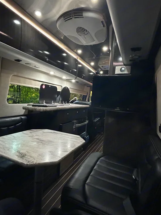 Inside a modern **rv rental**: well-lit, with a sleek kitchen, dining space, TV, and comfy seating.. Airstream Interstate 2016