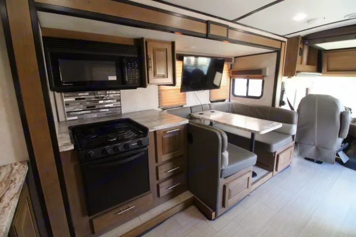 RV rental interior: functional kitchen with microwave & stove, backsplash, and a comfortable dining booth area.. Forest River FR3 2020