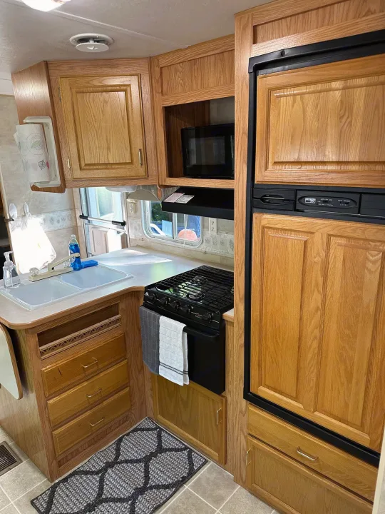 Cozy RV rental kitchen featuring a sink, stove, microwave, fridge, and oak cabinets. Ready for your next adventure!. Jayco Jay Flight 2003