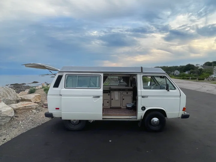 White Volkswagen Westfalia camper van parked by the ocean with doors open, ready for your next rv rental adventure.. Volkswagen Westfalia 1983