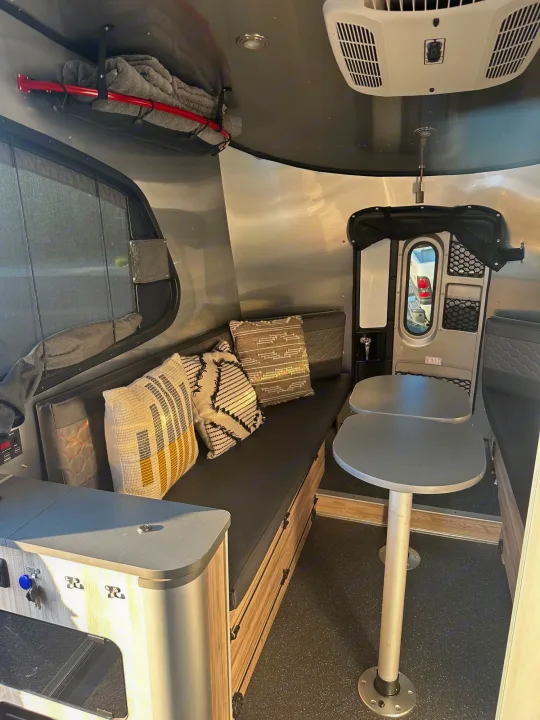 This RV rental's compact interior features a comfortable dinette area, bench seats, and smart overhead storage solutions.. Airstream Base Camp 2021
