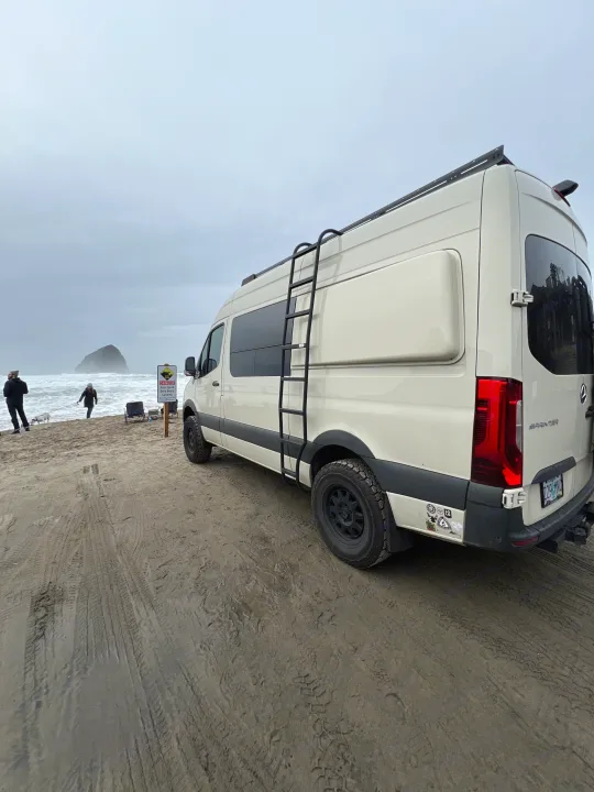 This RV rental Sprinter van, equipped for adventure, is parked on a sandy beach overlooking the ocean.. Mercedes-Benz Sprinter 2020