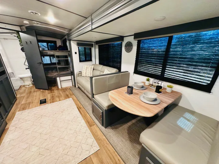 Spacious RV rental interior featuring a cozy dinette, sofa, and bunk beds, offering comfort for travelers.. Keystone RV Bullet Ultra Lite 2023