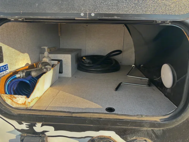 RV rental utility compartment with coiled power cord, water hose, hand sanitizer, and tools. Ready for your adventure.. Modern Buggy Little Buggy 10LR 2024
