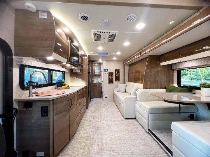 Bright & modern RV rental interior with a full kitchen, comfy sofa, and dining area, ready for your next adventure.. Entegra Coach Other 2023