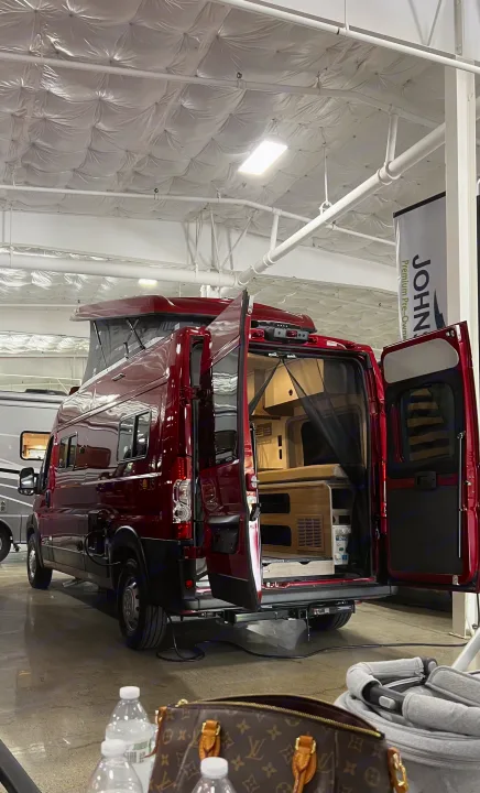 This vibrant red pop-top RV camper van, with its rear doors open revealing the living space, is ready for an RV rental.. Winnebago Solis 2023