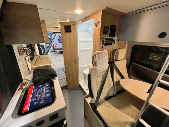 Modern Winnebago Solis camper van interior for rv rental, showing kitchen, bathroom, and seating with table.. Winnebago Solis 2023