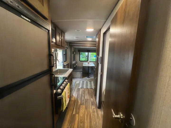 Tour an RV rental's cozy interior, featuring a Dometic fridge, kitchen, and dining booth. Wood floors and bright lighting.. Cruiser Rv Corp Other 2018