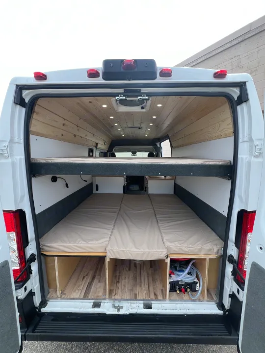 Custom RV rental camper van interior: wood ceiling, LED lights, upper bunk, and modular lower bed with storage.. Ram Promaster 2500 2021