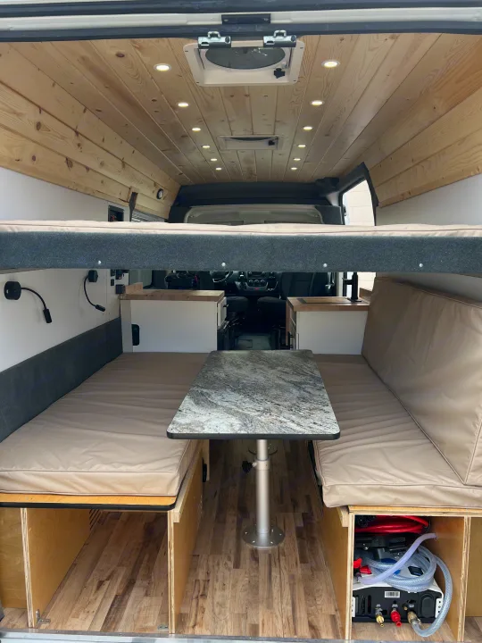 RV rental: Modern camper van interior with dinette, bunk bed, wood ceiling, and under-bench storage.. Ram Promaster 2500 2021