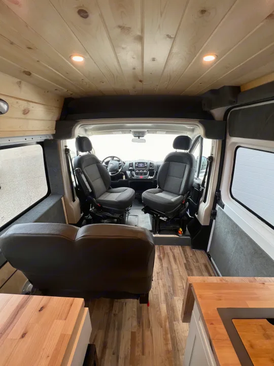 View inside a modern RV rental featuring wood ceilings, front seats, and a compact kitchen.. Ram Promaster 2500 2021