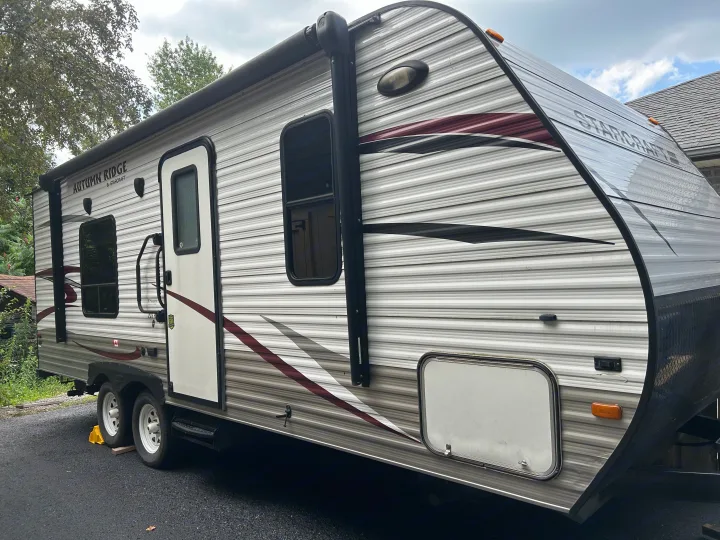 Side view of a parked gray & white Autumn Ridge travel trailer, an excellent RV rental option for camping trips.. Starcraft Autumn Ridge 2014