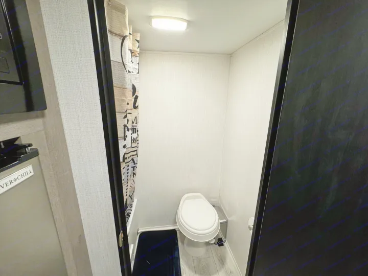 RV rental's compact wet bath features a toilet, shower curtain, and overhead lighting, maximizing space for travelers.. Cruiser RV Avenir 2024