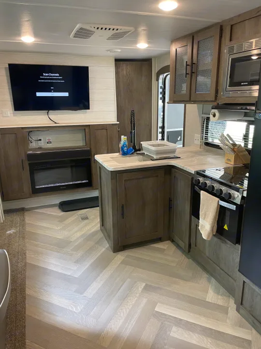 This RV rental features a stylish kitchen & living space with full amenities: stove, microwave, TV, and electric fireplace.. Forest River Wildwood 2021
