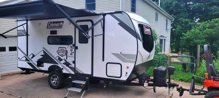Ready for adventure! A sleek white and gray Coleman Rubicon travel trailer, perfect for an rv rental, parked on a driveway with awning out.. Dutchmen Coleman Rubicon 2021
