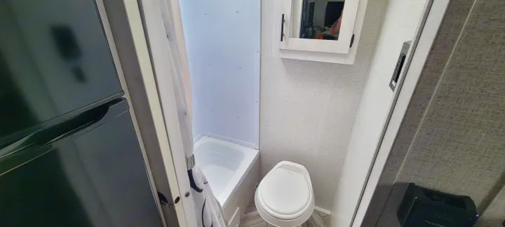 Compact RV rental interior showcasing a kitchenette fridge, full bathroom with toilet & tub/shower.. Dutchmen Coleman Rubicon 2021