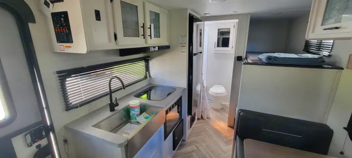Bright RV rental interior featuring a full kitchen, compact bathroom, dinette, and cozy bunk beds.. Dutchmen Coleman Rubicon 2021