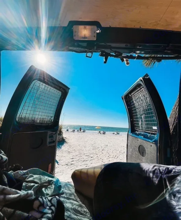 An RV rental provides this view: From inside a van, open doors reveal a bright sunny beach and blue ocean. Van life!. Ford Econoline 2010