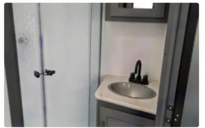 Compact RV rental bathroom with a glass shower enclosure and a modern sink vanity. Clean and functional.. Keystone RV Bullet Crossfire 2023
