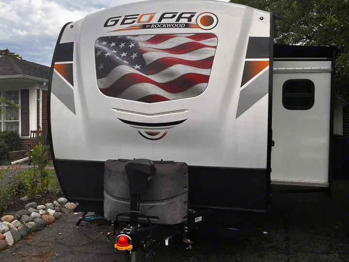 White Geo Pro RV rental with a striking American flag graphic, featuring the front hitch. Perfect for your next outdoor journey.. Forest River Rockwood Geo Pro 2021