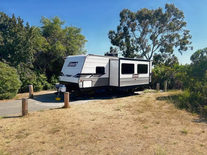 Coleman RV rental parked at a sunny campsite with dry grass and green trees. Perfect for outdoor adventures.. Coleman Lantern lt 2023