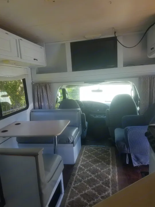 RV rental interior: A bright living space with a dining area, white cabinets, and front cockpit view.. four winds majestic 2004