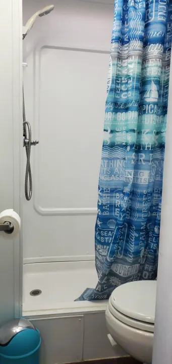 Compact RV rental bathroom with shower, toilet, and beach-themed curtain. Perfect for on-the-go adventures.. four winds majestic 2004