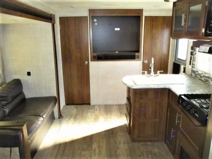 Spacious RV rental interior featuring a comfortable living area with sofa, full kitchen, and mounted TV for your adventures.. Gulf Stream Kingsport 2020