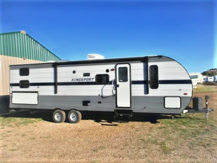 A gray and white Kingsport travel trailer, an RV rental option, parked outdoors under a clear blue sky.. Gulf Stream Kingsport 2020