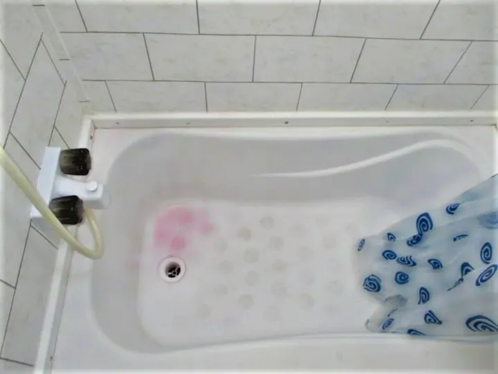 Compact RV rental bathroom: white tub with anti-slip bumps, shower head, patterned curtain.. Gulf Stream Kingsport 2020