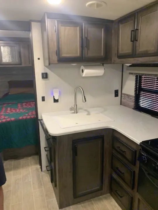 RV rental interior: A clean, well-equipped RV kitchenette featuring a sink, modern cabinetry, & a cozy adjacent bedroom area.. Heartland RVs Mallard 2021