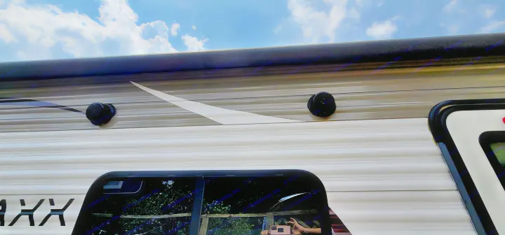 Side of an RV rental, showing outdoor speakers, striped siding, and a rolled-up awning against a cloudy blue sky.. Starcraft AR-One Maxx 2017