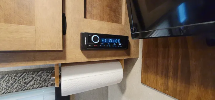 Inside an RV rental: a Furrion stereo, paper towel roll below, and wood cabinets. A TV is on the right.. Starcraft AR-One Maxx 2017