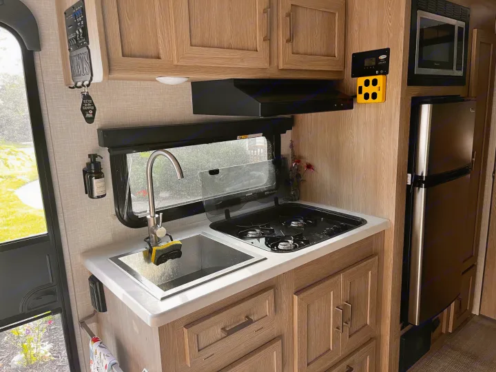 Inside an RV rental: a well-equipped galley with sink, stove, microwave, and fridge for on-the-go meals.. Forest River Rockwood Geo Pro 2021