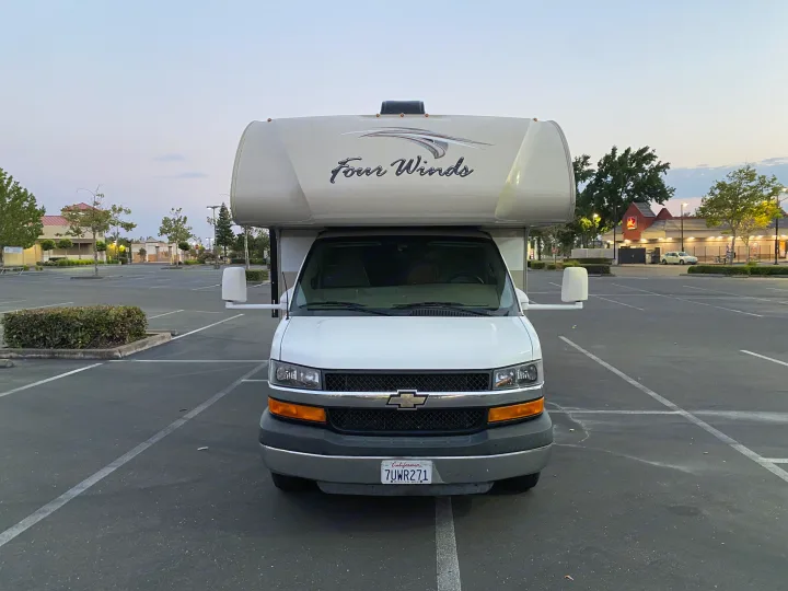 White Four Winds Class C RV rental parked in a large, empty lot at dusk. Ready for your next journey.. Thor Four Winds 2017
