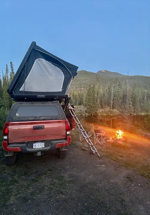 Enjoying the outdoors: red Tacoma with rooftop tent, ladder, campfire, and lake, like an RV rental for camping.. Toyota Tacoma TRD OFF ROAD 2018