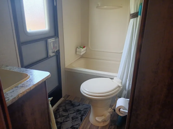 Compact RV rental bathroom featuring a toilet, integrated tub/shower, and small sink area.. Keystone RV Hideout LHS 2018