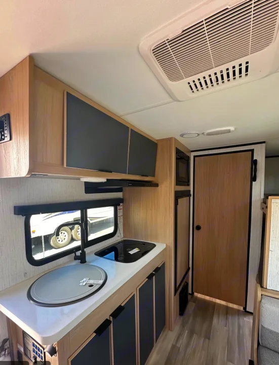 RV rental: well-appointed compact kitchen with sink, stove, microwave, fridge, and overhead cabinets in a modern interior.. Cruiser RV Hitch 2022