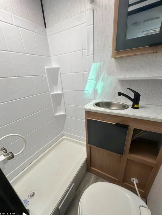 Compact RV rental bathroom with white tiled shower, sleek sink, and toilet for comfortable travel.. Cruiser RV Hitch 2022