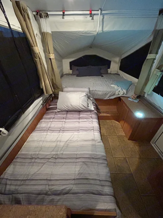 Inside a comfy rv rental, featuring two neatly made beds, curtains, and soft interior lighting for a relaxing night.. Forest River Rockwood Freedom 2012