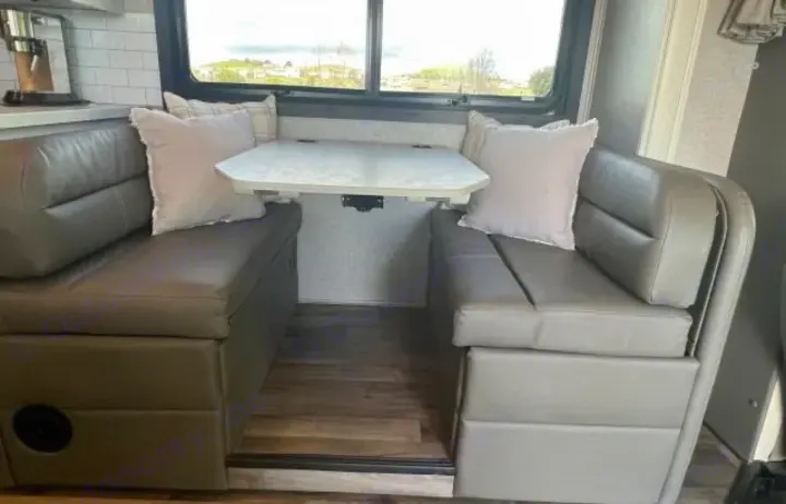 Spacious RV rental interior with a light gray dinette, adjustable table, and large window view. Great for journeys.. Jayco Greyhawk 2021