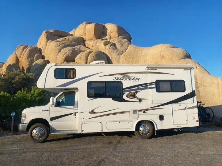 This white Sunseeker RV rental is parked among huge rock formations under a clear sky, perfect for a desert road trip.. Forest River Sunseeker 2014