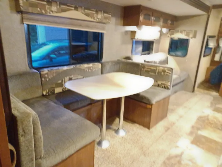 RV rental interior: Comfortable U-shaped dinette with a white table, ideal for dining with window views.. Coachmen Freedom Express Liberty Edition 2016