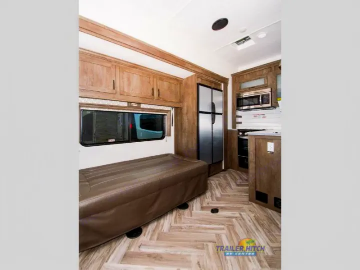 Explore this RV rental's inviting interior, featuring a well-equipped kitchen, large fridge, and versatile seating/sleeping area.. Forest River Stealth 2020