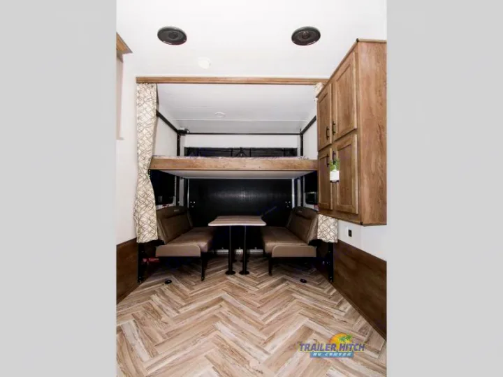 RV rental interior with a dining area, overhead bunk bed, and wood-grain cabinets.. Forest River Stealth 2020