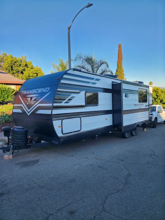 Spacious Transcend travel trailer, white with black accents, parked on asphalt. Perfect for an RV rental adventure!. Grand Design Transcend Xplor 2024