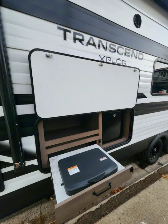 Open outdoor kitchen on a Transcend Xplor RV rental, featuring a fridge, storage, and pull-out counter with cooking surface.. Grand Design Transcend Xplor 2024